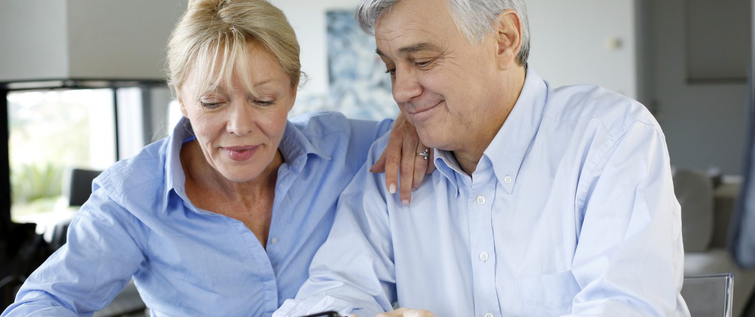 Senior couple calculting bills amount using smartphone