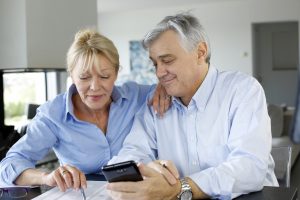Senior couple calculting bills amount using smartphone
